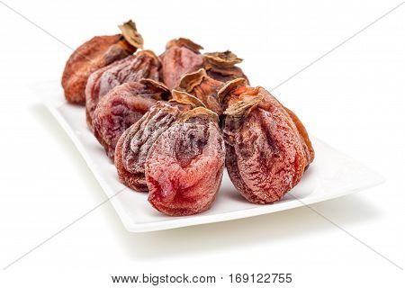 Several dried persimmon isolated on white plate