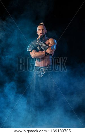 Young and muscular man performing a theatrical pose on a stage. Very sexy man in stage costume