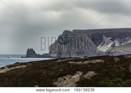 North Coast Scotland - June 6 2012: Huge cliffs tower over Durness Beach a sandy patch looking north on a rough coast among rock cliffs and sprinkled pieces of rock.