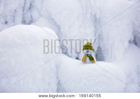 Incredible beautiful interesting white snow froze in strange textures forms and snowflakes and among all this beauty there is a little snowman in a hat and scarf.