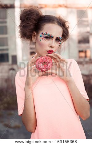 Beauty fashion model girl taking colorful donuts. Funny joyful woman with sweets, dessert. Diet, dieting concept. Junk food, Slimming, weight loss. Fashionable girl with creative makeup and doughnut