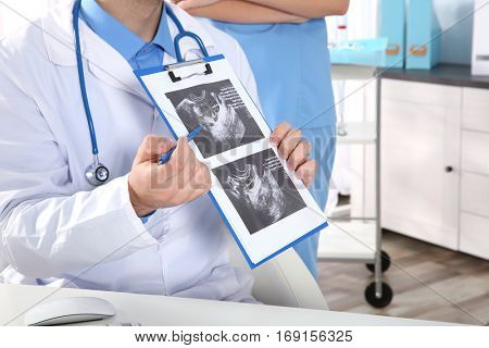Doctor showing baby ultrasound image to pregnant woman