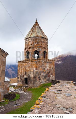 Gergeti Trinity Church Or Tsminda Sameba in the morning mist near village Stepantsminda, Georgia. Mount Kazbegi. Spring Or Summer Season.