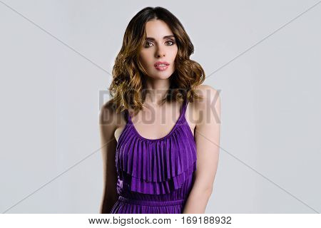 Portrait of beautiful woman in purple dress on a light background
