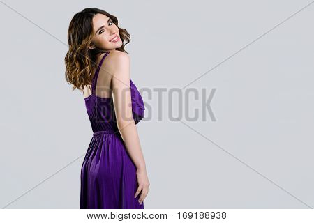 Beautiful brunette in violet dress on light background