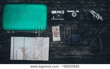 Vintage hipster suitcase packing before travel with old suitcase camera and accessories on a wooden table top view
