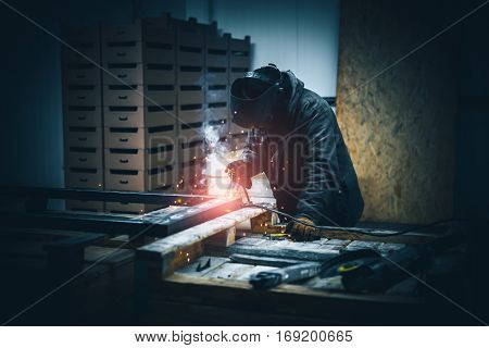 Welder working a welding metal with protective mask and sparks