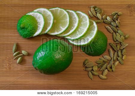 Green lime slices with cardamom seeds on a bamboo board