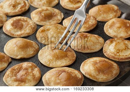 Baking Dutch mini pancakes called poffertjes in a special skillet pan