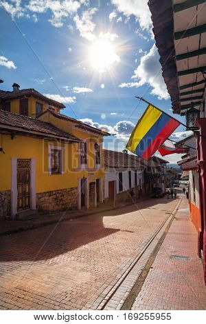 The Colombian flag flies over a cobbelstone street in the Candelaria neighborhood of Bogota Colombia.