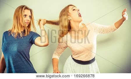 Aggressive mad women fighting each other pulling hair. Two young girls struggling win catfight. Violence.