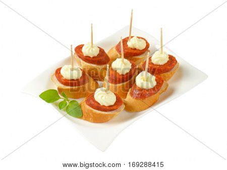 Bread based canapes with spicy sausage and creamy spread