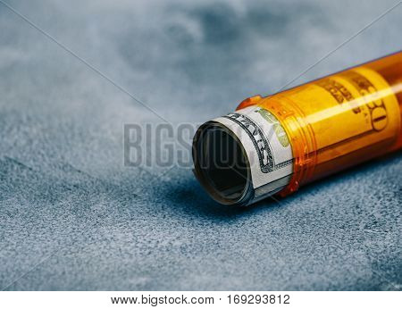 Money Bills in orange pill bottle on table background. medical concept with copyspace
