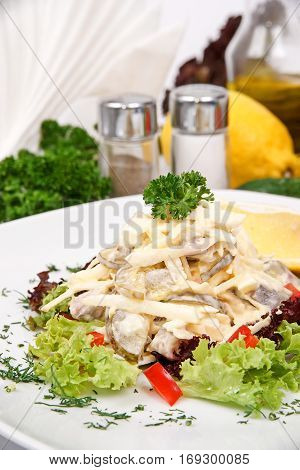 Herring salad with red pepper on a white plate with fresh herbs
