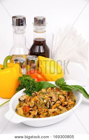 Fried mussels with vegetables and herbs on a white plate