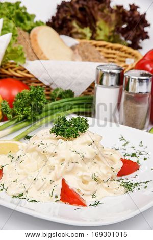 Squid salad with cream cheese on a white plate with spices and herbs
