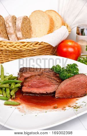 Steak in red wine with a side dish of asparagus on a white plate