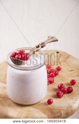 Smoothies with frozen red currants in jar on a wooden stand.