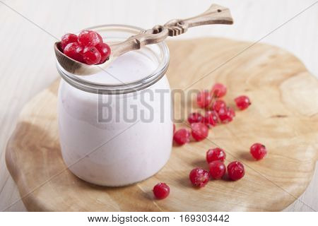 Smoothies with frozen red currants in jar on a wooden stand.
