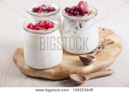 Homemade yogurt with frozen berries red currants black currants raspberries and cranberries in three banks