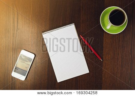 close-up, pen, notepad near phone and cup of coffee at wooden desk