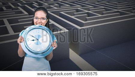 Delighted businesswoman holding a clock against entrance to difficult maze puzzle