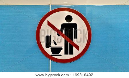 Sign prohibits throwing bottles and foreign objects down the pan in a public toilet