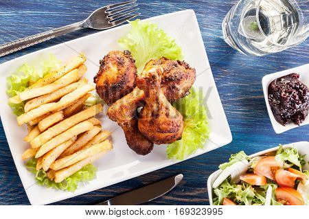 Chicken drumsticks with chips on a plate. Selective focus