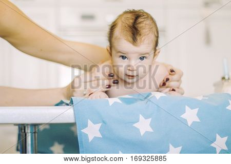small child learns to help parents keep his head. baby lying on a blue diaper in a star. parental support.