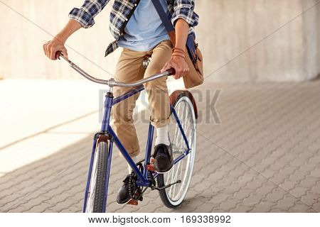 people, style, leisure and lifestyle - young hipster man with shoulder bag riding fixed gear bike on city street