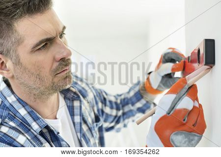 Mid-adult man marking on wall with level