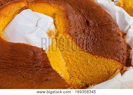 Close up of a sliced Pao de Lo, the Portuguese sponge cake shown in its most traditional form, with the typical paper sheets used on the baking, isolated on white background