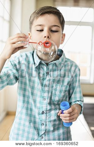 Cute boy playing with bubble wand at home