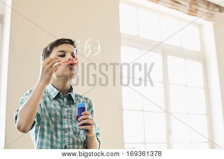 Boy blowing bubbles at home