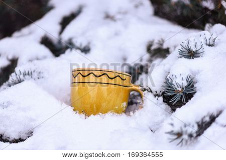 yellow ornamented with waves cup outdoor on snowy firry tree branches on natural background selective focus