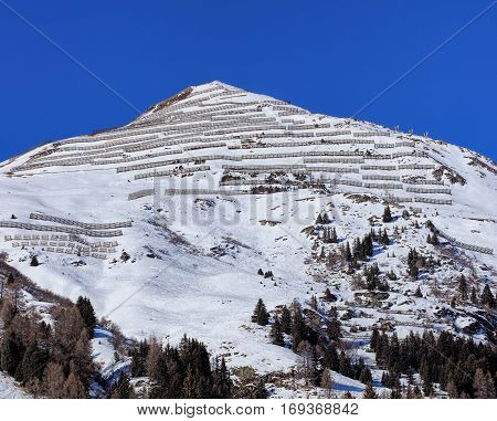 Summit of a mountain with snow fences for avalanche control, view from the town of Davos in the Swiss canton of Grisons in wintertime.