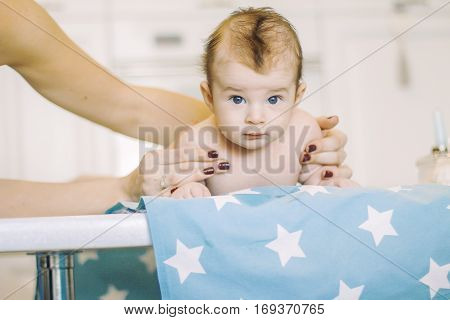 small child learns to help parents keep his head. baby lying on a blue diaper in a star. parental support.