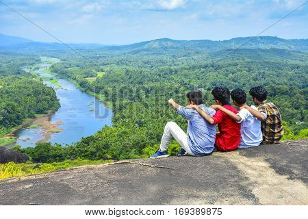 Happiness summer friendship concept. Group of friends spending time together having fun outdoor looking on river back view