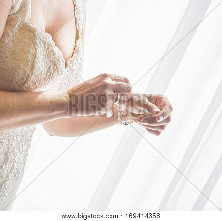 Bride on her wedding day. Already dressed in her wedding dress, she wears a bracelet.