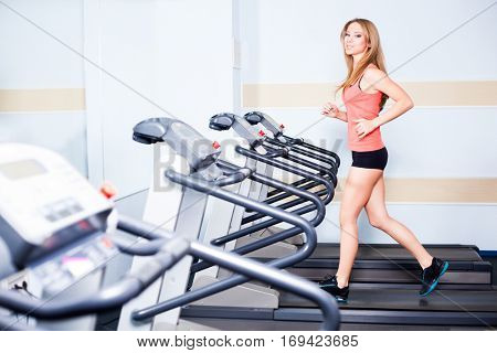 Active young woman running on treadmill at the gym exercising. Run on a machine.