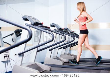 Active young woman running on treadmill at the gym exercising. Run on a machine.