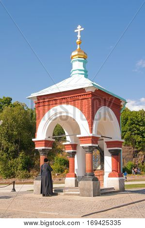 priest baptized in front of the chapel. Chapel of All Who Sorrow joy. Russia Karelia Valaam Island.