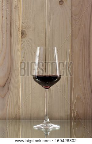 brilliant glass with red wine on a wooden background on a glass stand