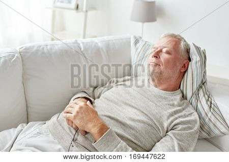 old age, rest, comfort and people concept - senior man sleeping on sofa at home