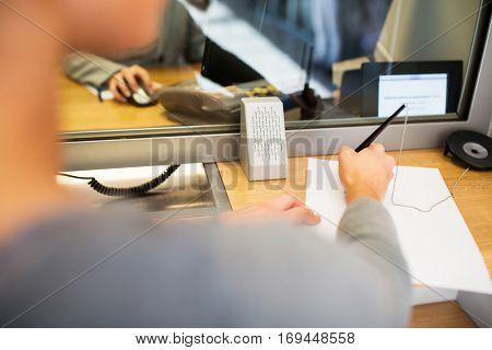 people and finance concept - customer with pen and paper writing application at bank office