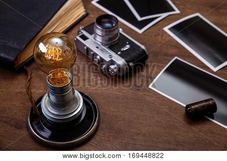 Vintage photo camera. Blank photo frames. Old aged album. Retro lamp light bulb. Old camera rolls. Wooden rustic background.