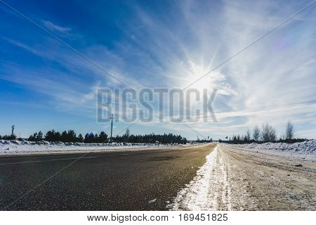 Asphalt road in snowy winter on beautiful frosty sunny day. Trip or journey in countryside