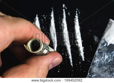 Drug Abuse. Hand of man holds rolled banknote for snorting line of cocaine powder. Problems with drugs concept. Top view.