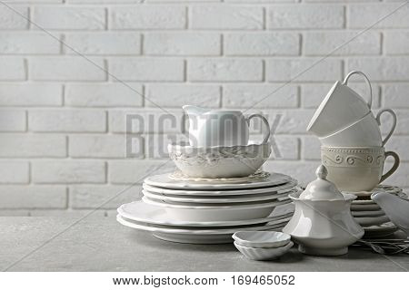 Porcelain dishware on table and white brick wall background