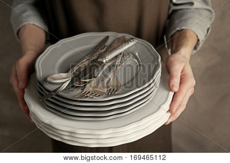 Female hands holding pile of dishware, closeup